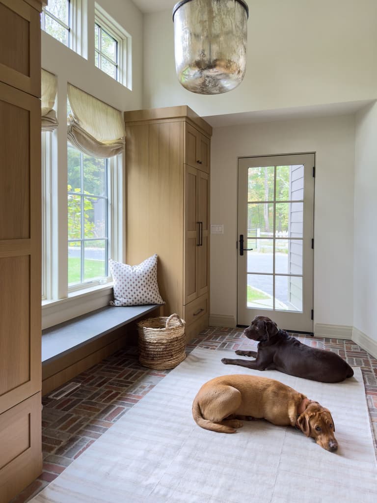 Built-in mudroom bench under a window beside full-height oak cabinetry in a Mendham, NJ renovation by Michael Robert Construction