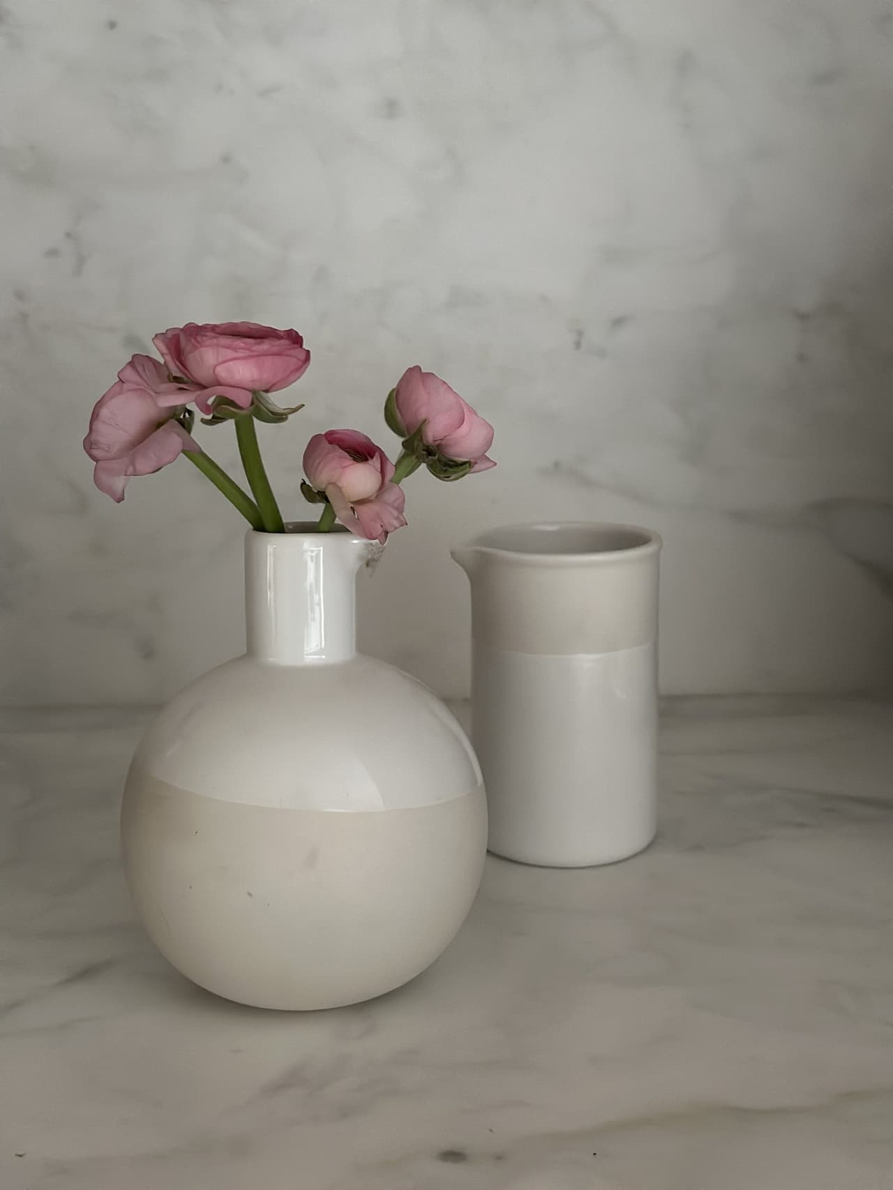 Pink ranunculus in a dipped-glaze vase on a marble counter in a Westfield, NJ kitchen styled by Ellie Mroz Design