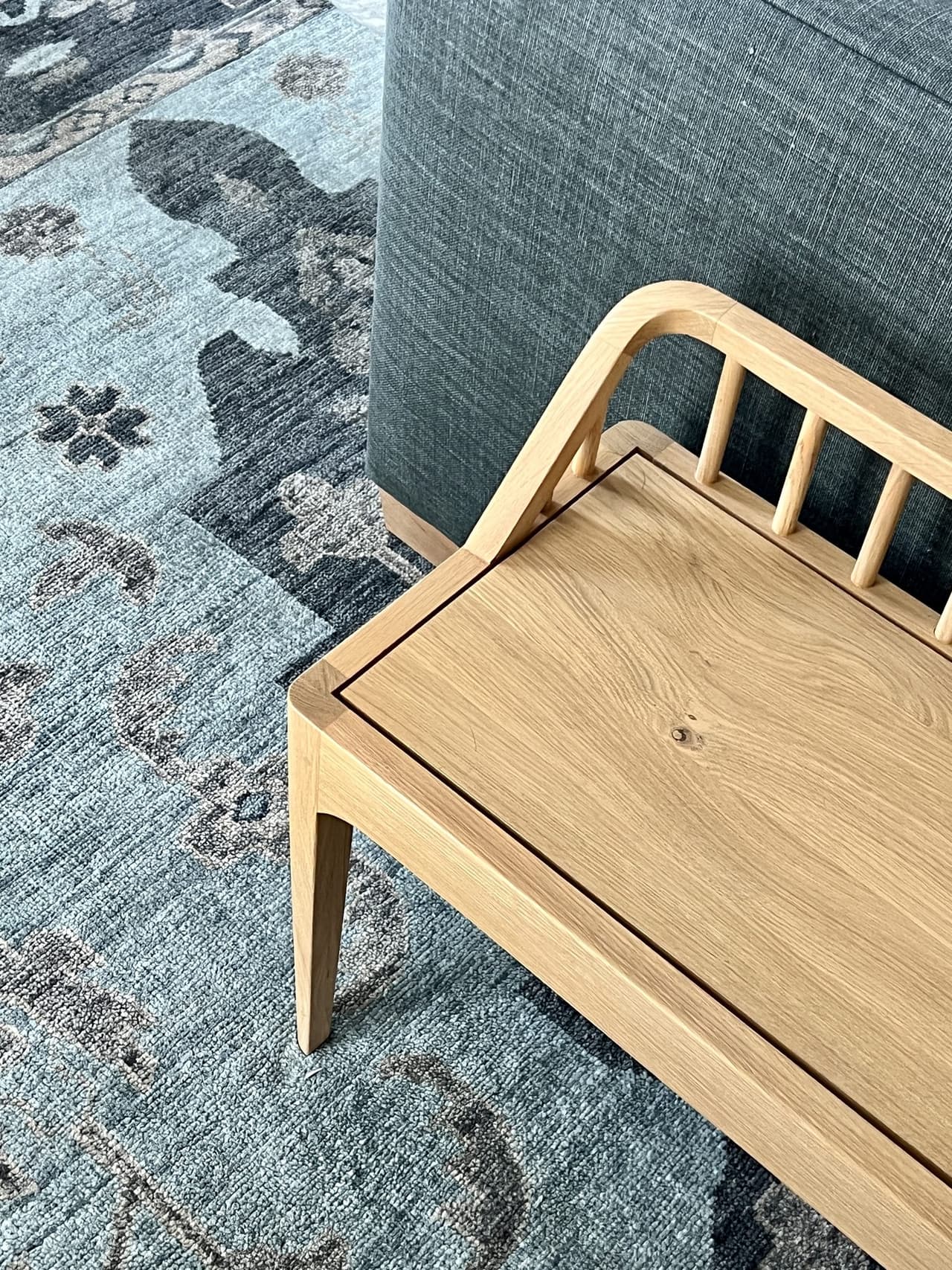White oak spindle bench at the foot of a bed on a patterned wool rug in a Westfield, NJ bedroom by Ellie Mroz Design