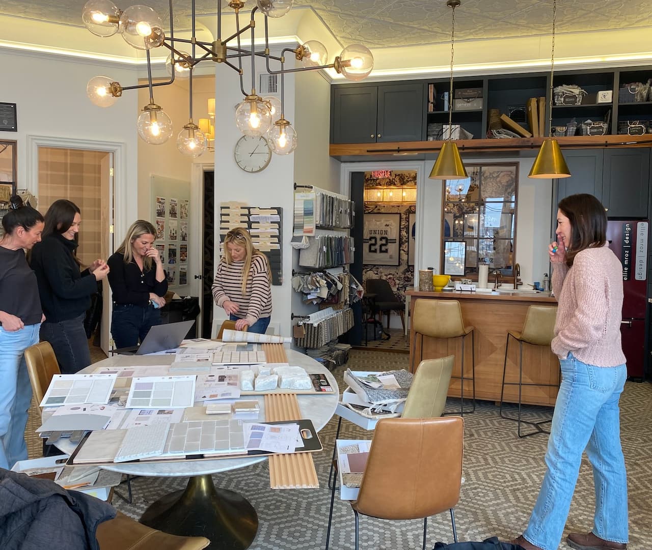 The Ellie Mroz Design team reviewing tile, stone, fabric and paint selections spread across the studio table in Westfield, NJ