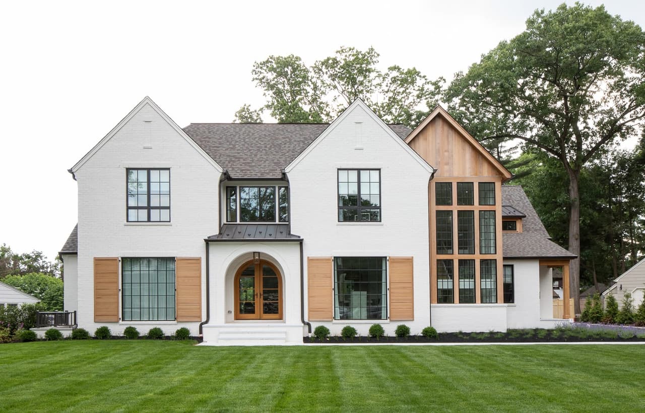 Front elevation of a white brick custom home with cedar shutters and an arched entry in Westfield, NJ, built by Michael Robert Construction