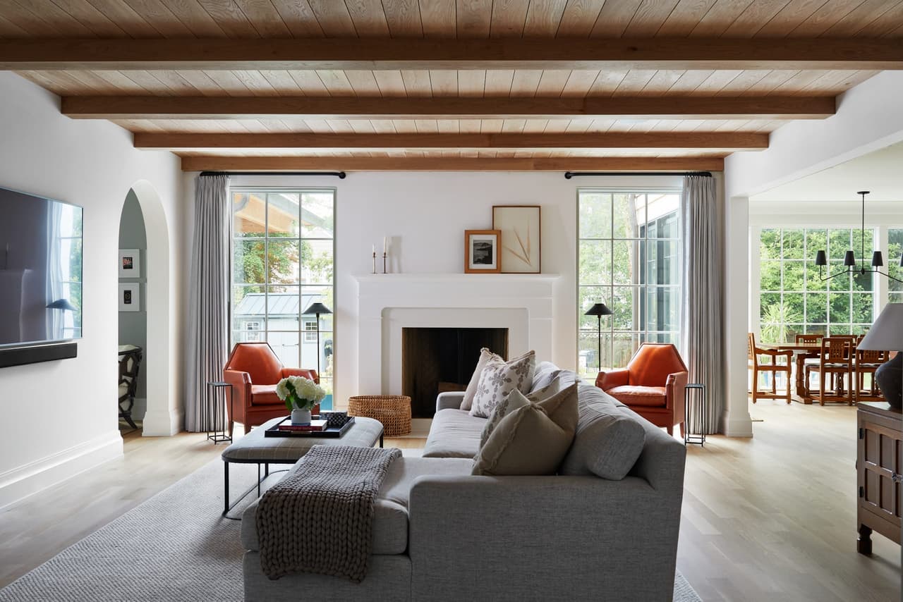 Open-concept family room in a Westfield, NJ custom home by Michael Robert Construction, with a planked ceiling on exposed beams, an arched opening and a fireplace between sliding doors