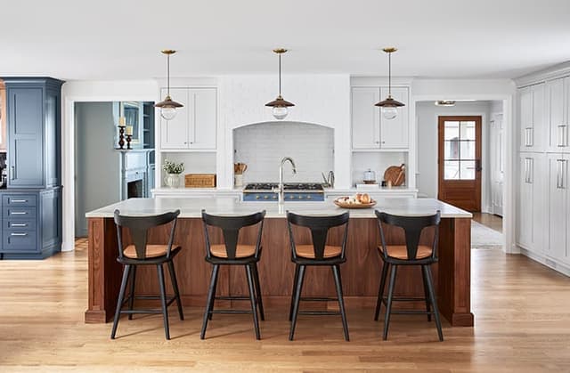 Walnut kitchen island with black stools facing a brick-arched range alcove in a Westfield, NJ addition and whole-home renovation by Michael Robert Construction