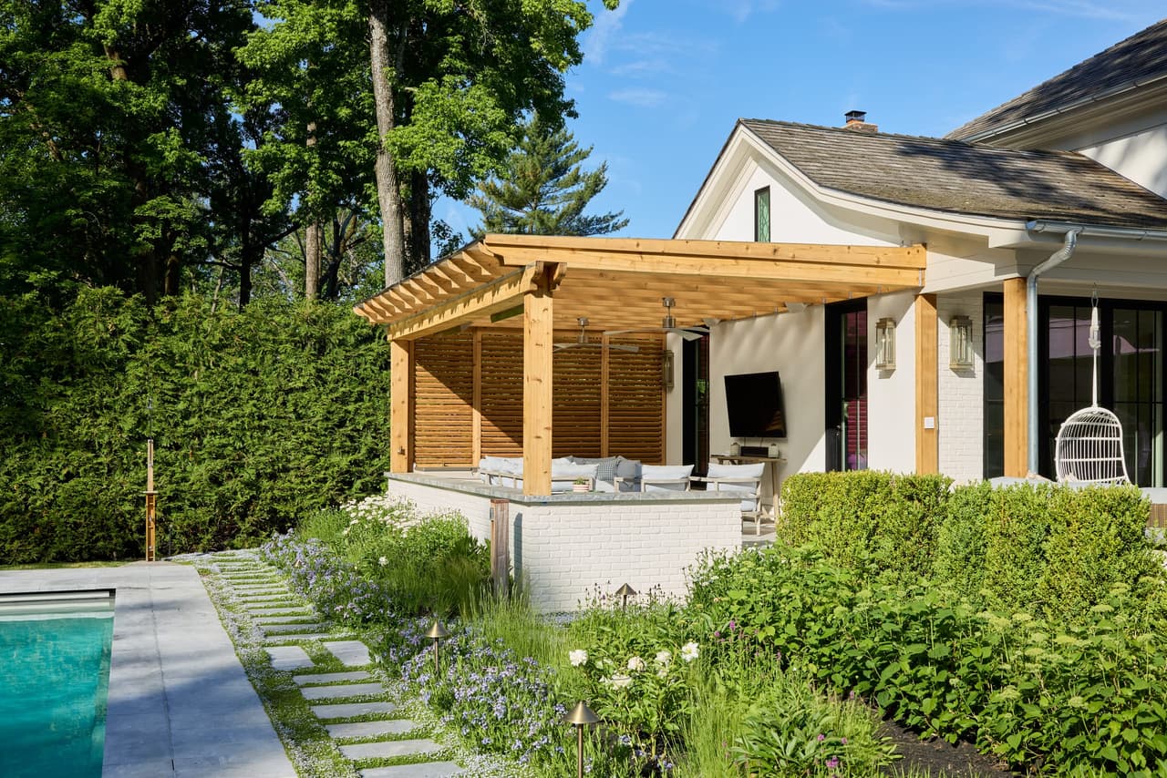 Cedar pergola shading a poolside lounge and outdoor television at a Westfield, NJ home by Michael Robert Construction